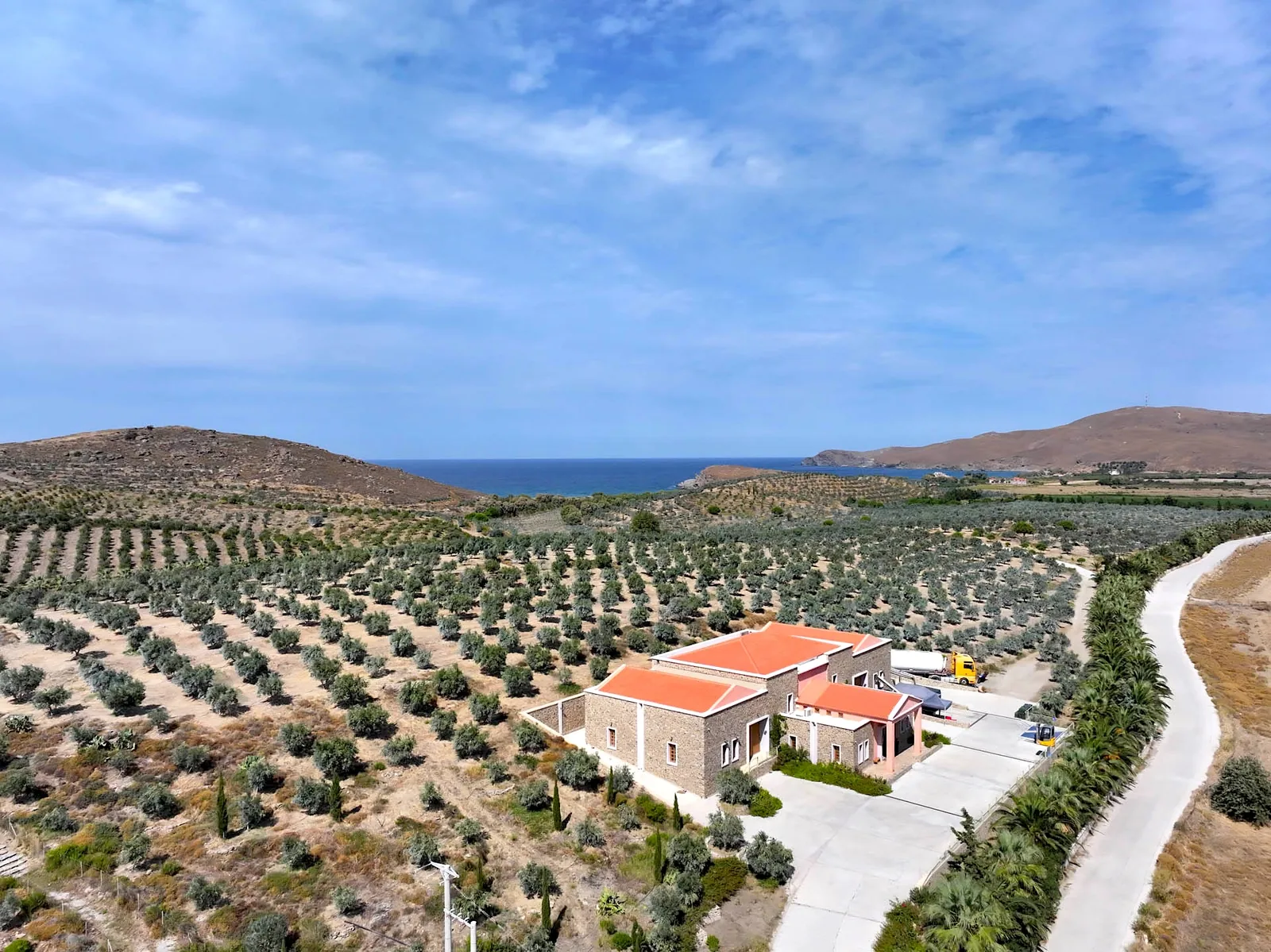 Ελαιώνες που κατεβαίνουν ως τη θάλασσα, με το ελαιοτριβείο ανάμεσά τους